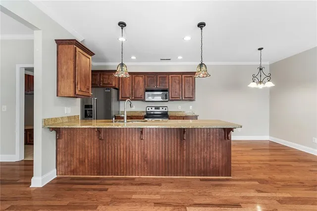 a open kitchen with stainless steel appliances granite countertop a sink a stove a refrigerator and a wooden floors
