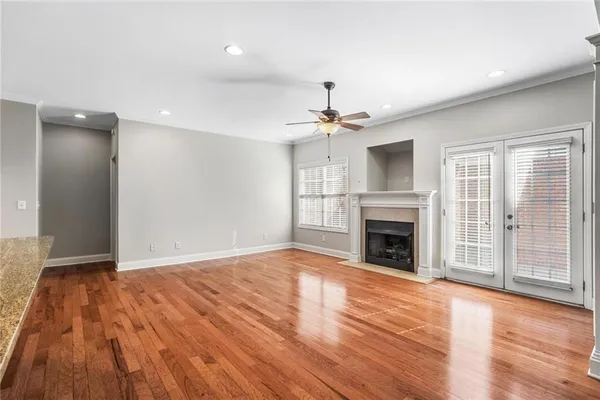 a view of an empty room with wooden floor fireplace and a window