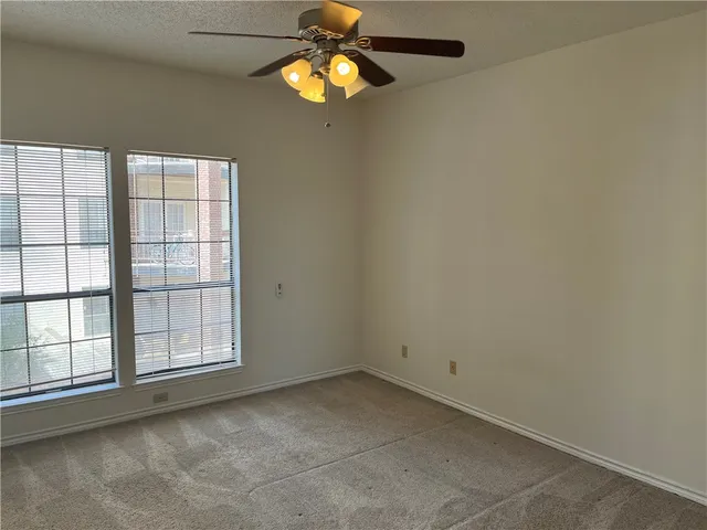 an empty room with windows and fan