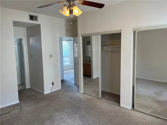 an empty room with closet and a chandelier fan