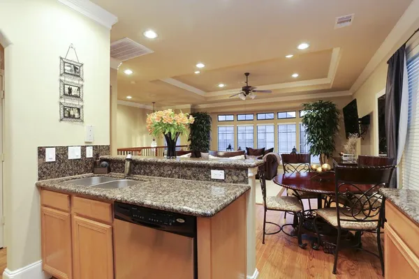 a kitchen with granite countertop a stove a sink a dining table and chairs
