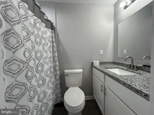 a bathroom with a granite countertop sink a toilet and a mirror