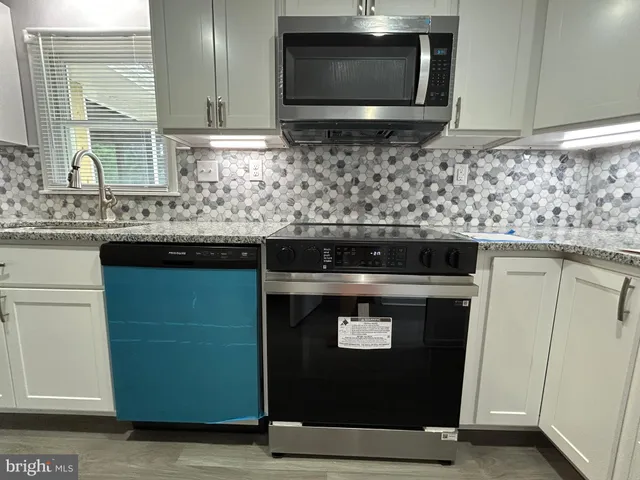 a kitchen with stainless steel appliances granite countertop a sink stove and cabinets