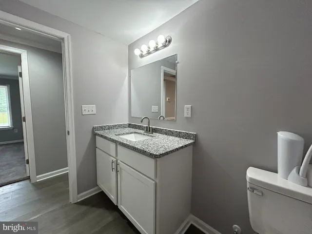 a bathroom with a granite countertop toilet sink and mirror