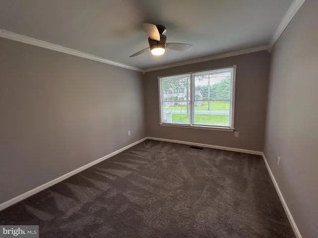 an empty room with windows and ceiling fan