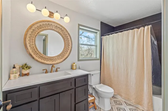 a bathroom with a sink mirror a toilet and a window
