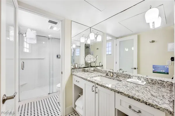 a bathroom with a granite countertop sink a mirror and a shower