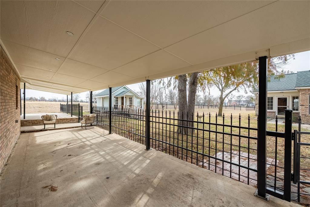 364 Parker Road, Unit A Van Alstyne, TX 75495 - Photo 38 of 39 Covered area all around the secondary garage/workshop and separate living quarters or office. Covered concrete patio featuring brick exterior wall, black metal fencing, and stone accents