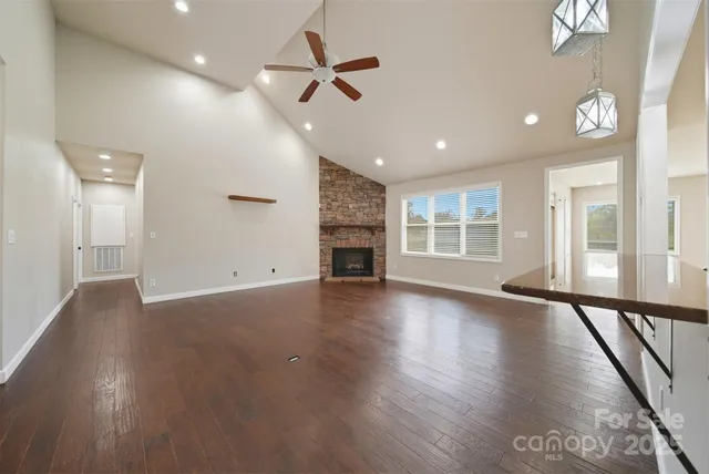 an empty room with wooden floor fireplace and windows