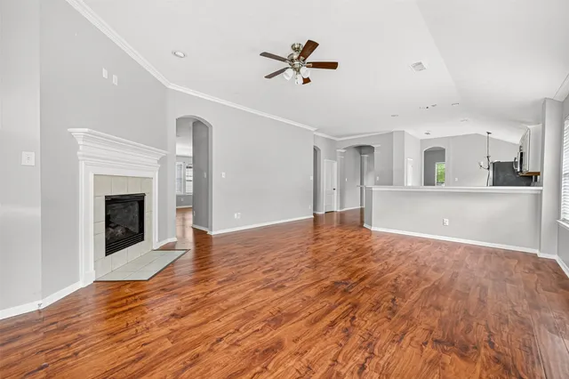 a view of a livingroom with a fireplace a ceiling fan and wooden floor