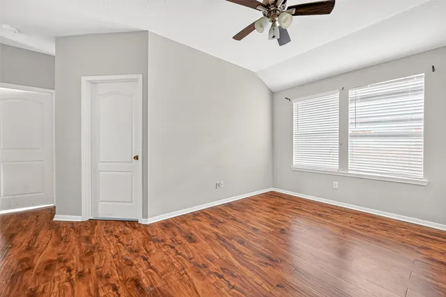 a view of empty room with wooden floor and ceiling fan