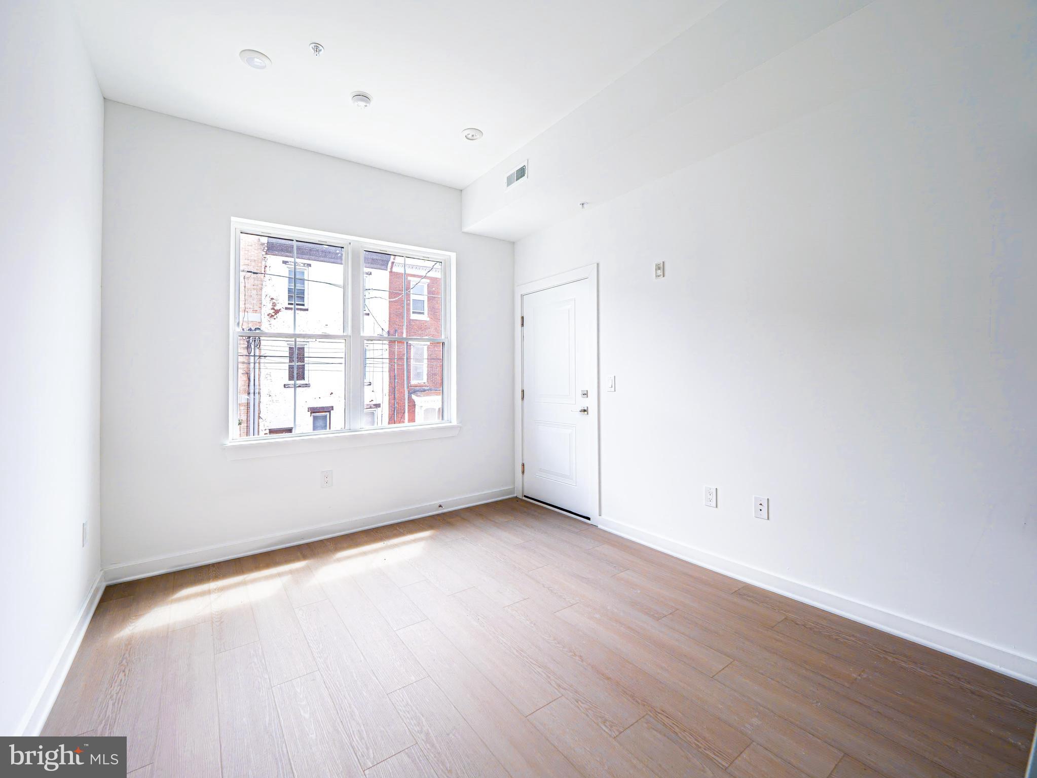 2403-2407 West Thompson Street, Unit 4 Philadelphia, PA 19121 - Photo 4 of 13 an empty room with wooden floor and windows