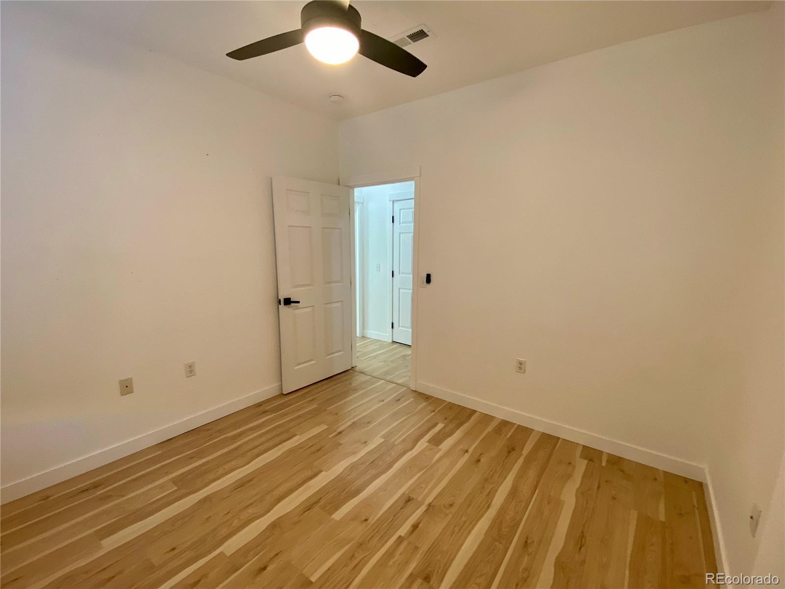 6722 South Winnipeg Circle, Unit 103 Aurora, CO 80016 - Photo 16 of 19 an empty room with a chandelier fan and wooden floor