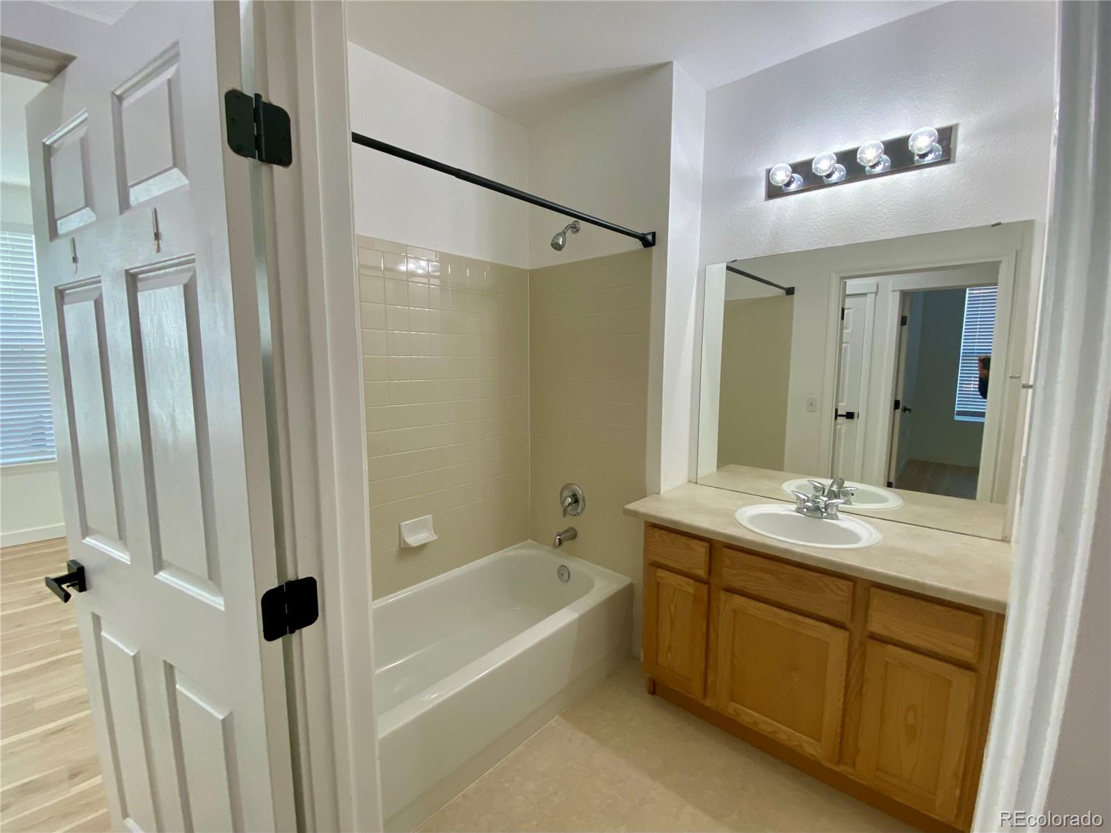 6722 South Winnipeg Circle, Unit 103 Aurora, CO 80016 - Photo 17 of 19 a bathroom with a granite countertop sink a mirror a vanity and a bathtub
