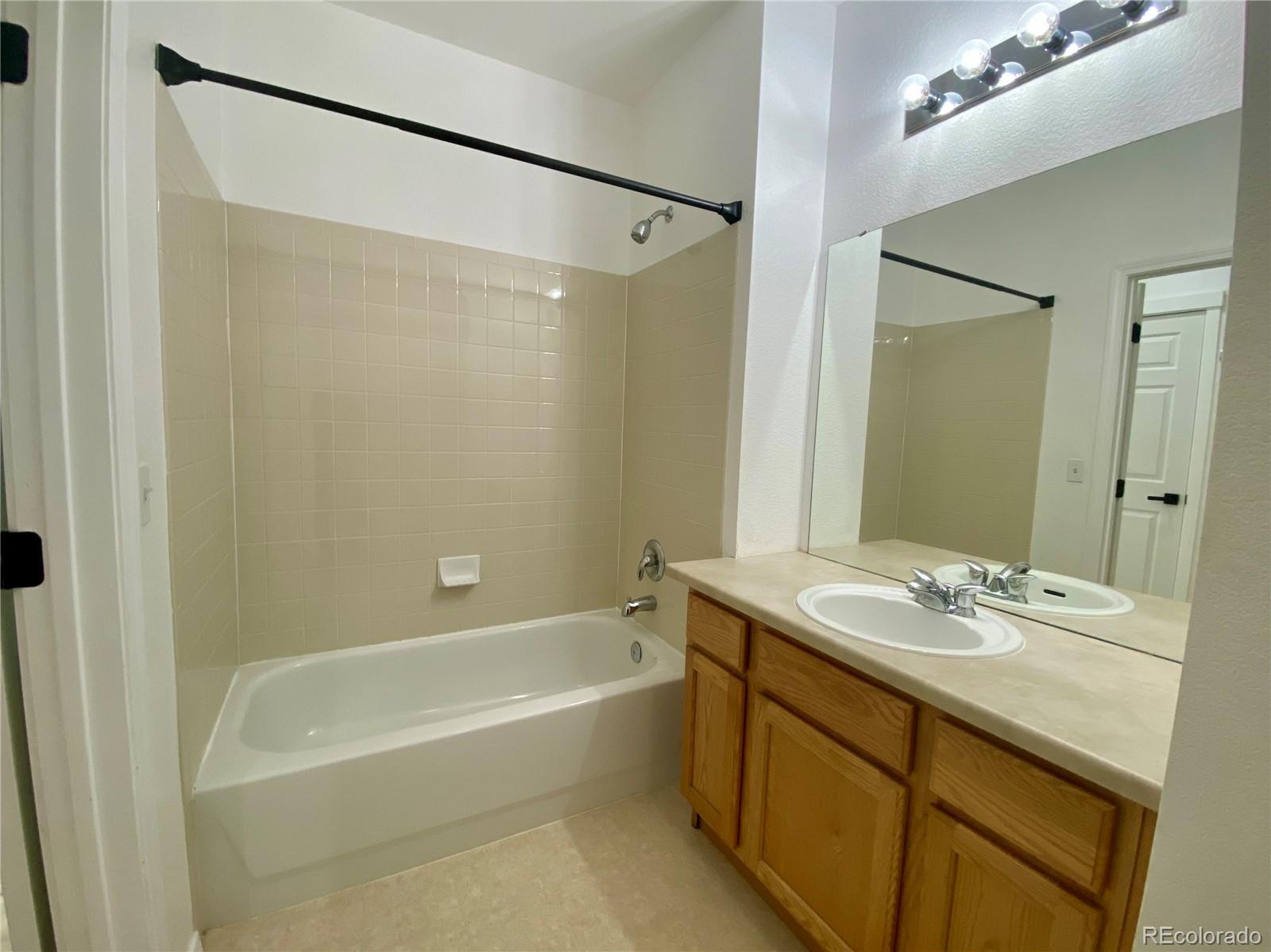 6722 South Winnipeg Circle, Unit 103 Aurora, CO 80016 - Photo 18 of 19 a bathroom with a granite countertop sink mirror and a bath tub