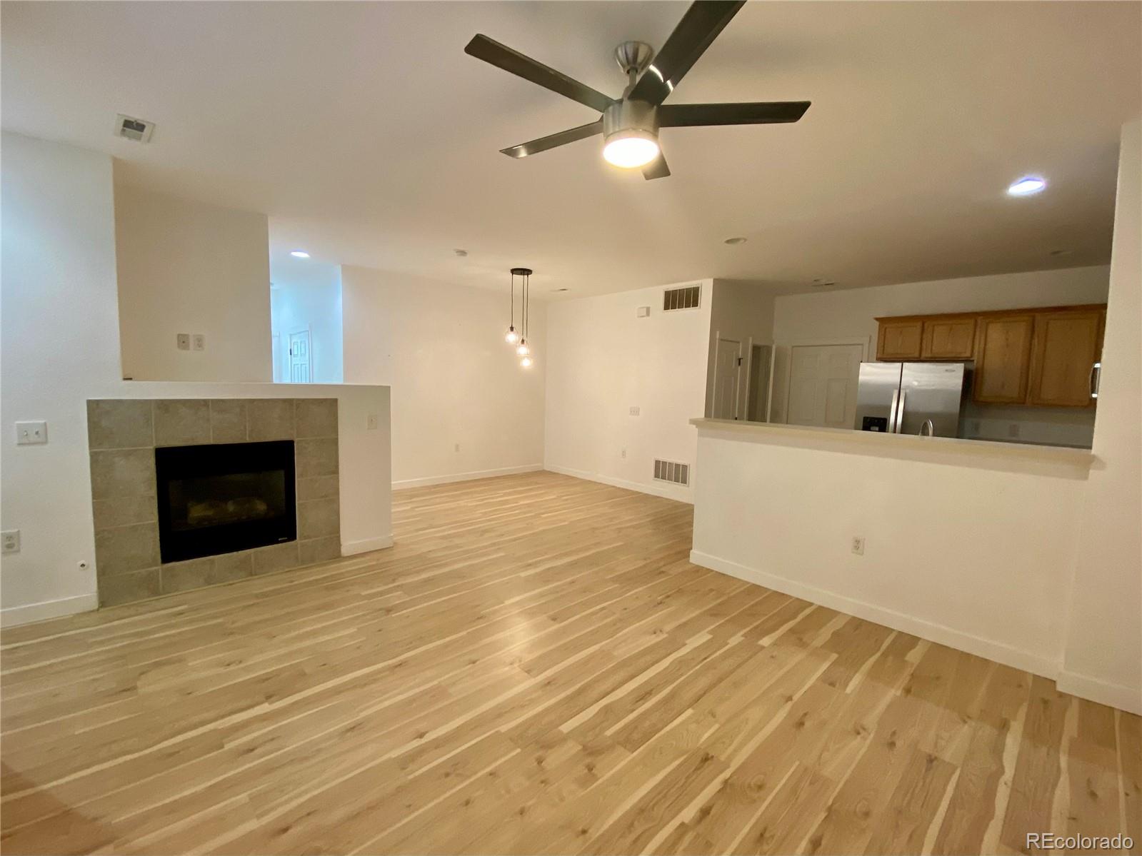 6722 South Winnipeg Circle, Unit 103 Aurora, CO 80016 - Photo 5 of 19 a view of a livingroom with a fireplace a ceiling fan and wooden floor