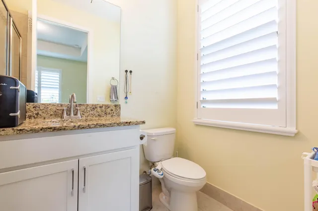 a bathroom with a granite countertop sink toilet and mirror