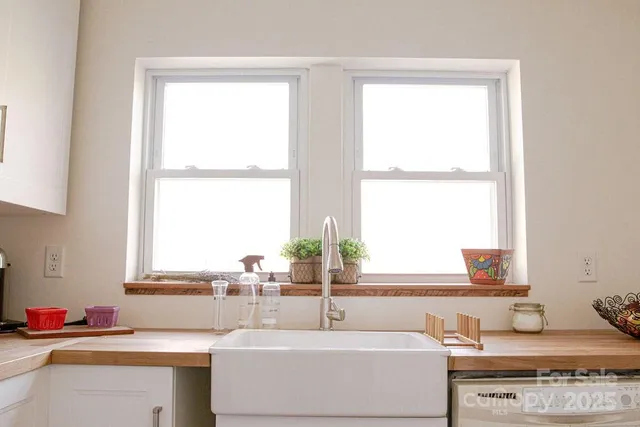 a kitchen with white cabinets a sink and dishwasher next to a window
