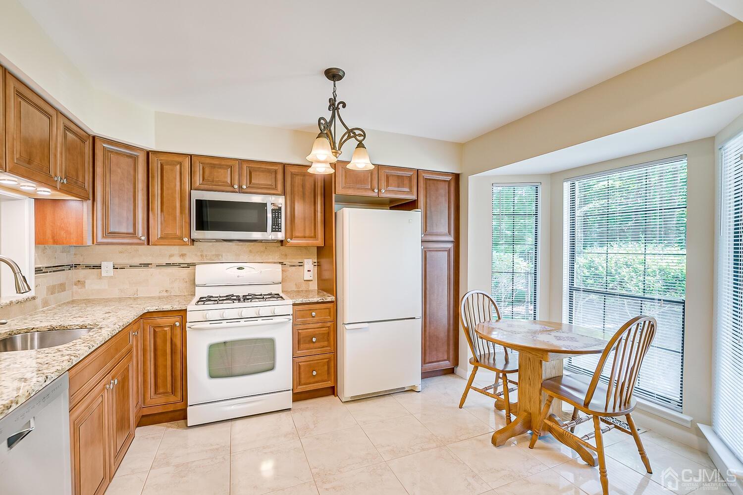 1606 Timber Oaks Road Edison, NJ 08820 - Photo 8 of 33 a kitchen with stainless steel appliances granite countertop a stove a refrigerator a microwave a dining table and chairs with wooden floor