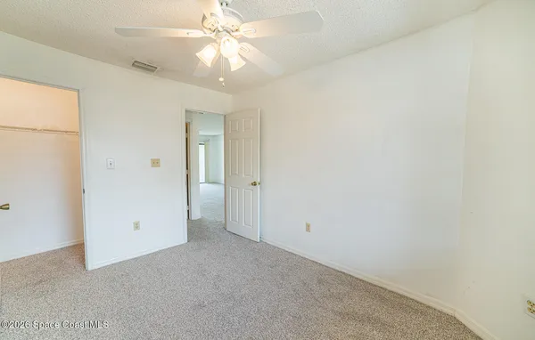 an empty room with a ceiling fan and a window
