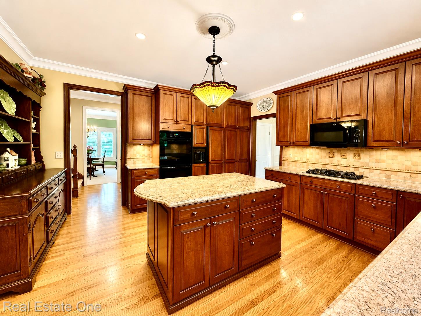 1793 Skyline Drive Rochester, MI 48306 - Photo 10 of 38 Kitchen featuring wood-finish flooring, an island with a light-toned countertop, extensive wood cabinetry, and a gas cooktop