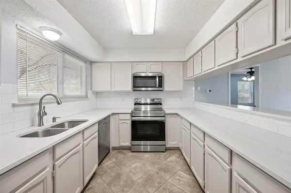 a kitchen with stainless steel appliances granite countertop a sink and a stove top oven with white cabinets
