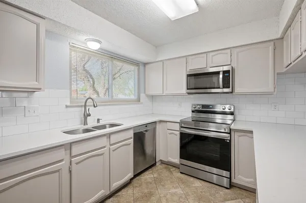 a kitchen with cabinets stainless steel appliances and a sink