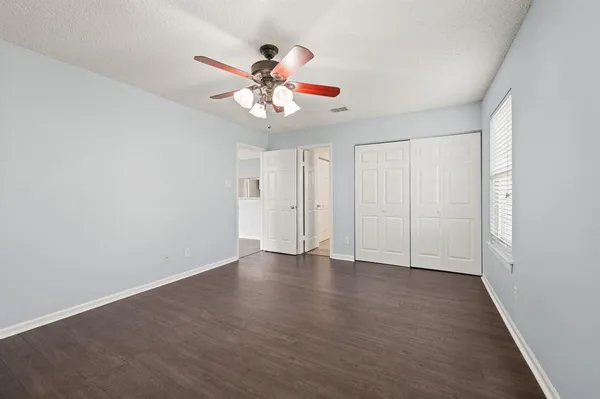 an empty room with windows and fan