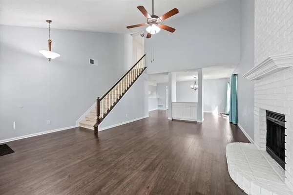 a view of an empty room with wooden floor a ceiling fan and a window