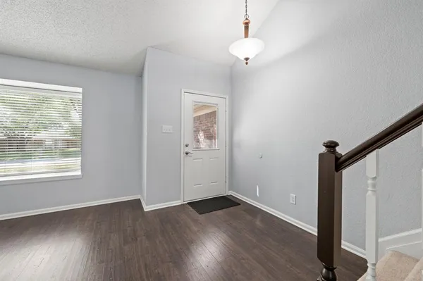 an empty room with wooden floor cabinet and windows
