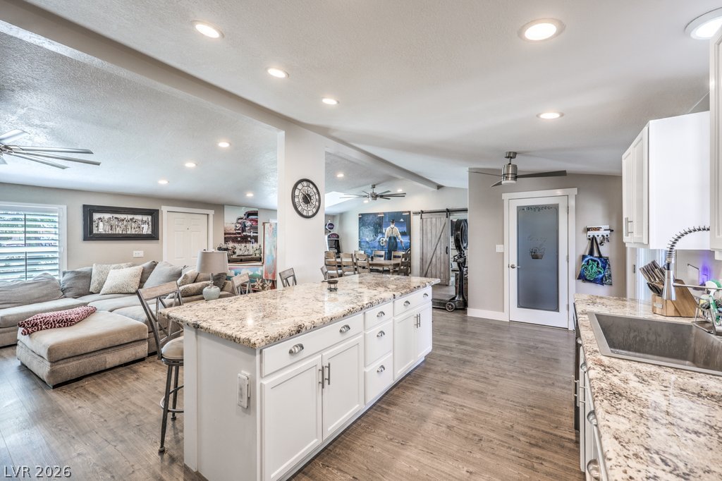4375 Pinwheel Street Logandale, NV 89021 - Photo 7 of 52 Granite counters and wood flooring flow through this inviting open-concept living space, featuring a kitchen island and plentiful recessed lighting.