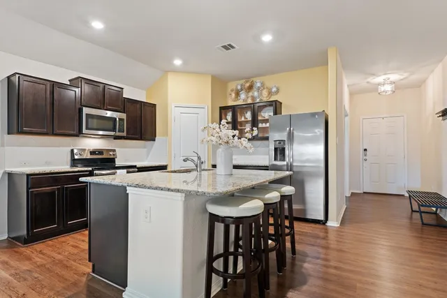 a kitchen with stainless steel appliances granite countertop a table chairs stove and refrigerator