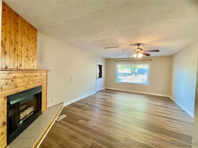 a view of an empty room with a fireplace and wooden floor