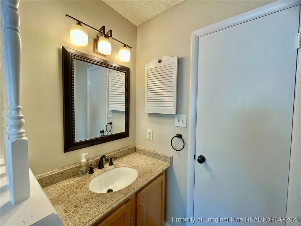 1505 Diamond Road Fayetteville, NC 28311 - Photo 17 of 21 a bathroom with a granite countertop sink and a mirror