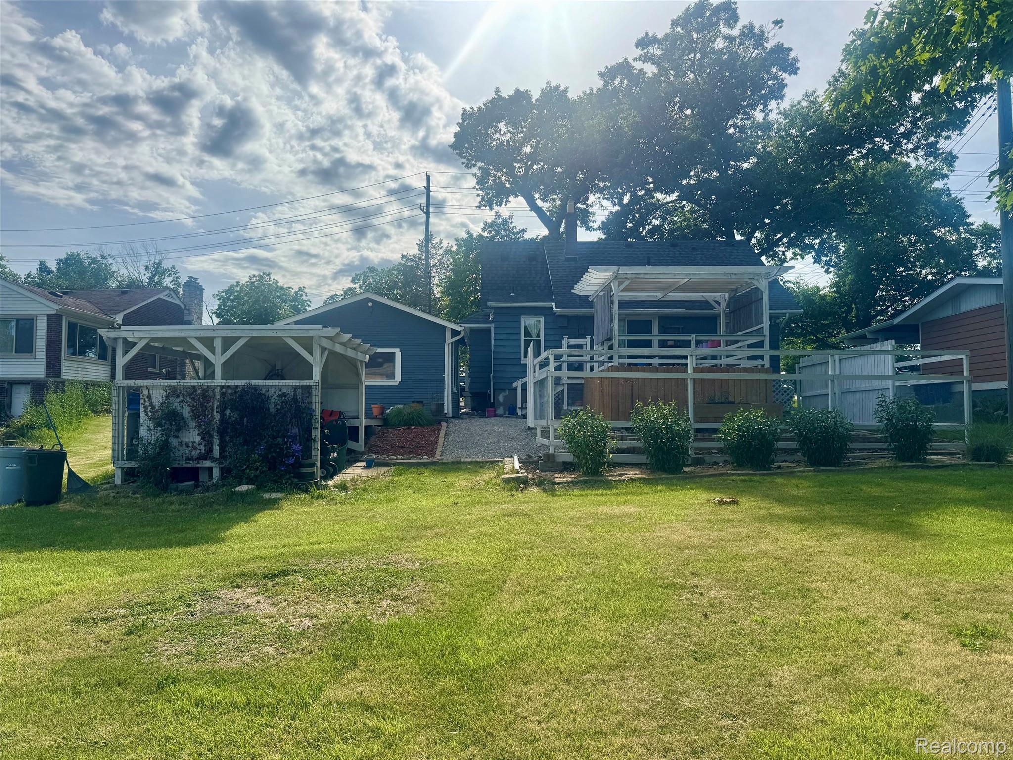 22827 Meridian Road Grosse Ile, MI 48138 - Photo 3 of 36 Expansive backyard featuring a large elevated deck with white railings, a pergola-covered patio, and a separate covered structure