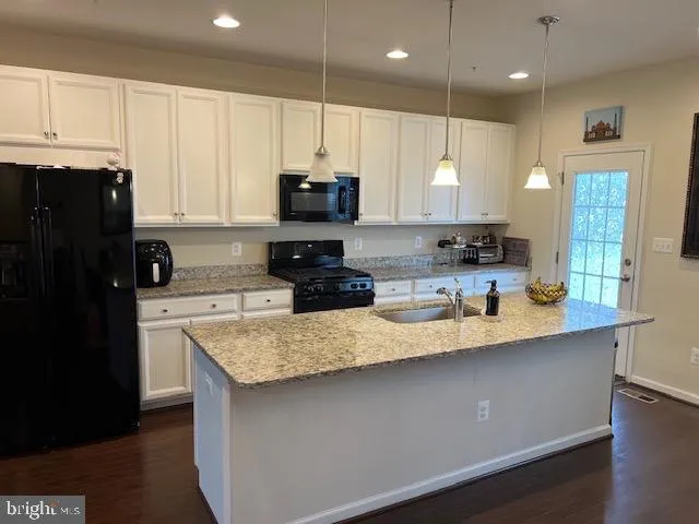 an open kitchen with wooden floor and stainless steel appliances