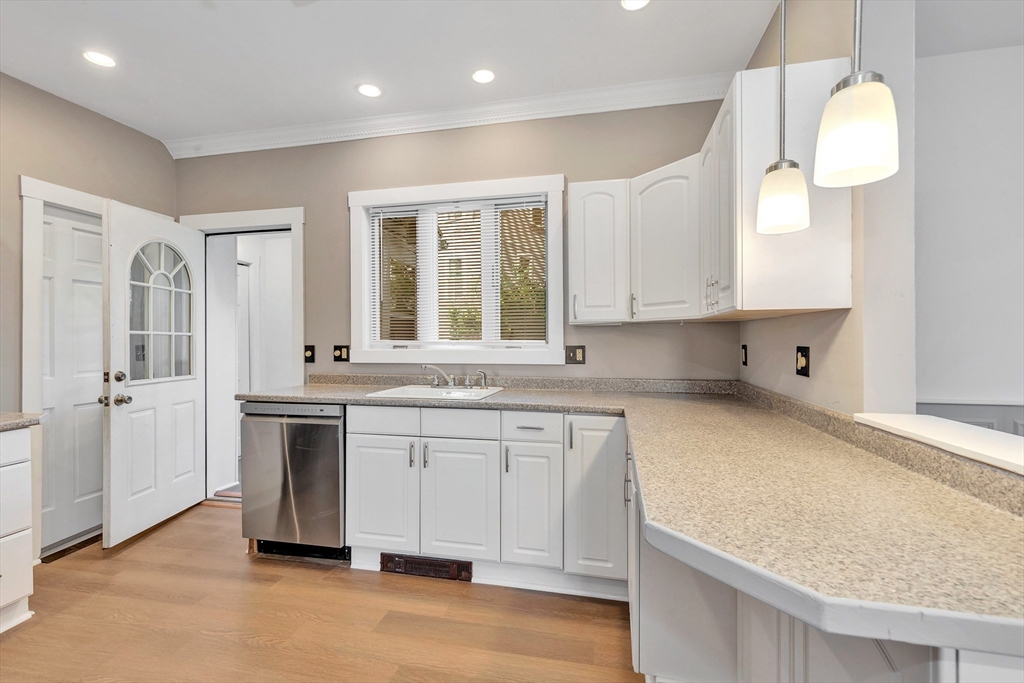 24 Taylor Street, Unit 1 Gloucester, MA 01930 - Photo 13 of 29 a kitchen with granite countertop a sink white cabinets and stainless steel appliances