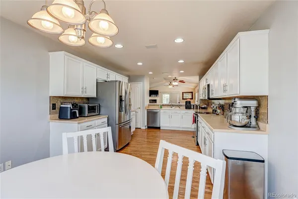a kitchen with stainless steel appliances kitchen island granite countertop a sink dishwasher a stove a microwave oven with cabinets and wooden floor