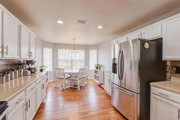 a kitchen with stainless steel appliances a refrigerator a stove top oven and a dining table with wooden floor