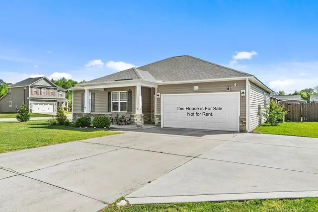 a view of a brick house with a yard and large tree