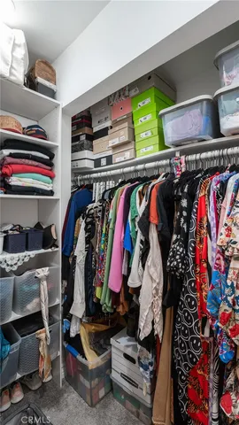 a view of walk in closet with clothes and shoes