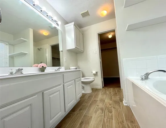a spacious bathroom with a double vanity sink a toilet and a mirror
