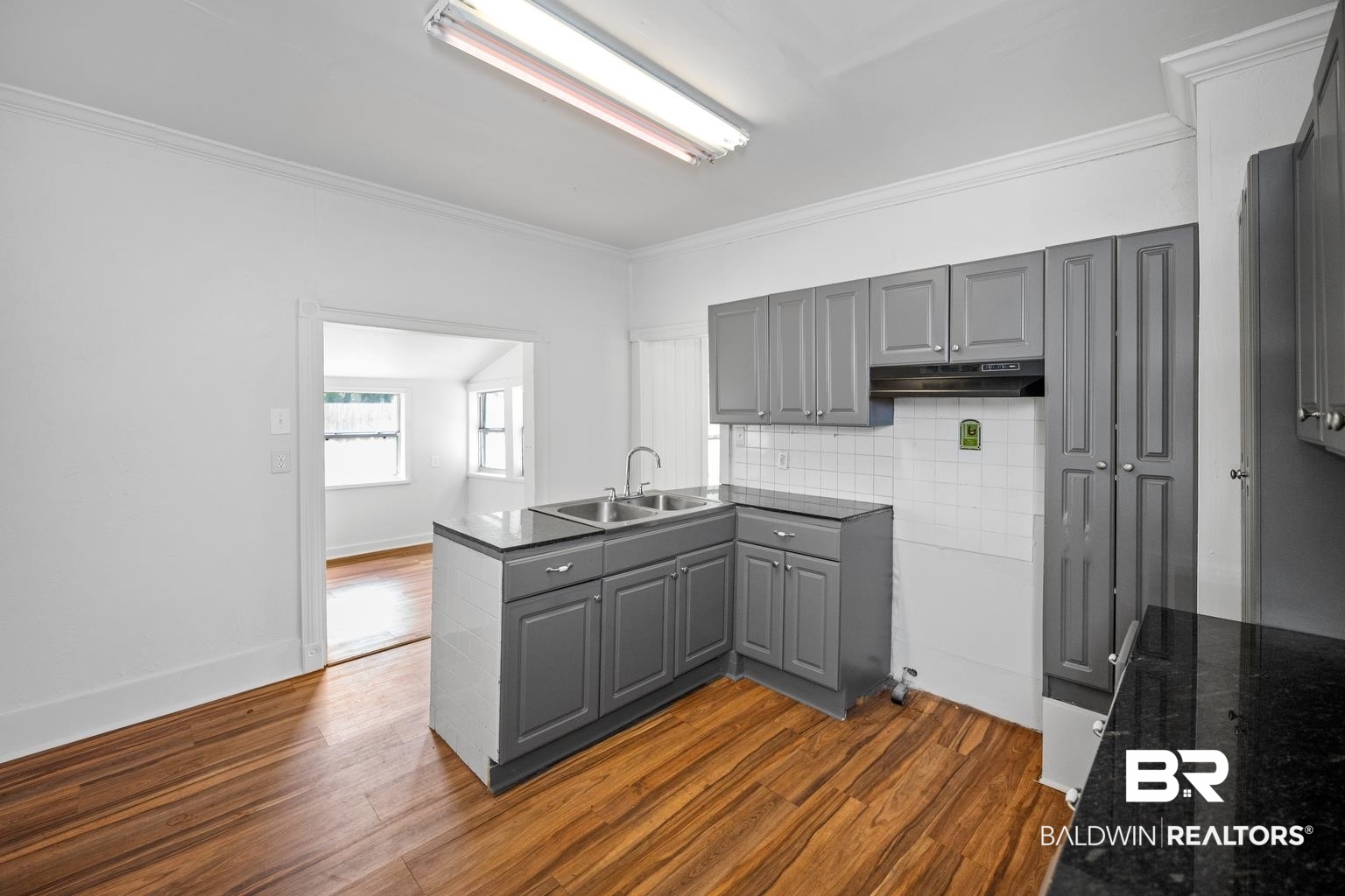19575 Keller Road Foley, AL 36535 - Photo 12 of 17 Kitchen with gray cabinetry, a peninsula, dark wood-style flooring, crown molding, and tasteful backsplash