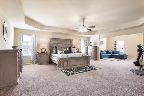a bedroom with a bed a chair and potted plant on the dresser