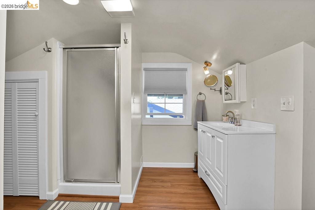 325 South 2nd Street Rio Vista, CA 94571 - Photo 21 of 33 Bathroom featuring a glass-enclosed shower, wood-finish flooring, a white vanity with a single sink, a wall-mounted medicine cabinet, and a window with blinds