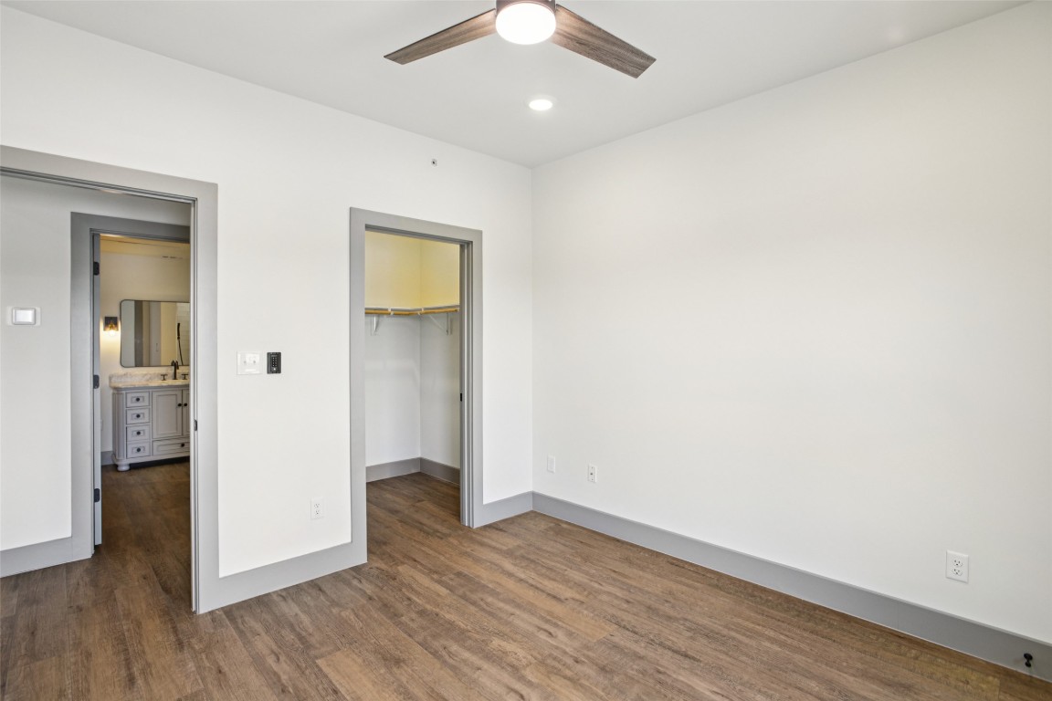 2450 Wickersham Lane, Unit 1917 Austin, TX 78741 - Photo 13 of 18 Unfurnished bedroom with a walk in closet, recessed lighting, dark wood-type flooring, and ceiling fan