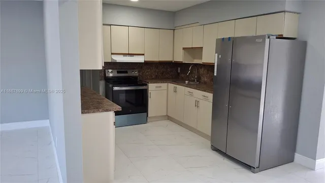 a kitchen with stainless steel appliances granite countertop a refrigerator a stove and a sink