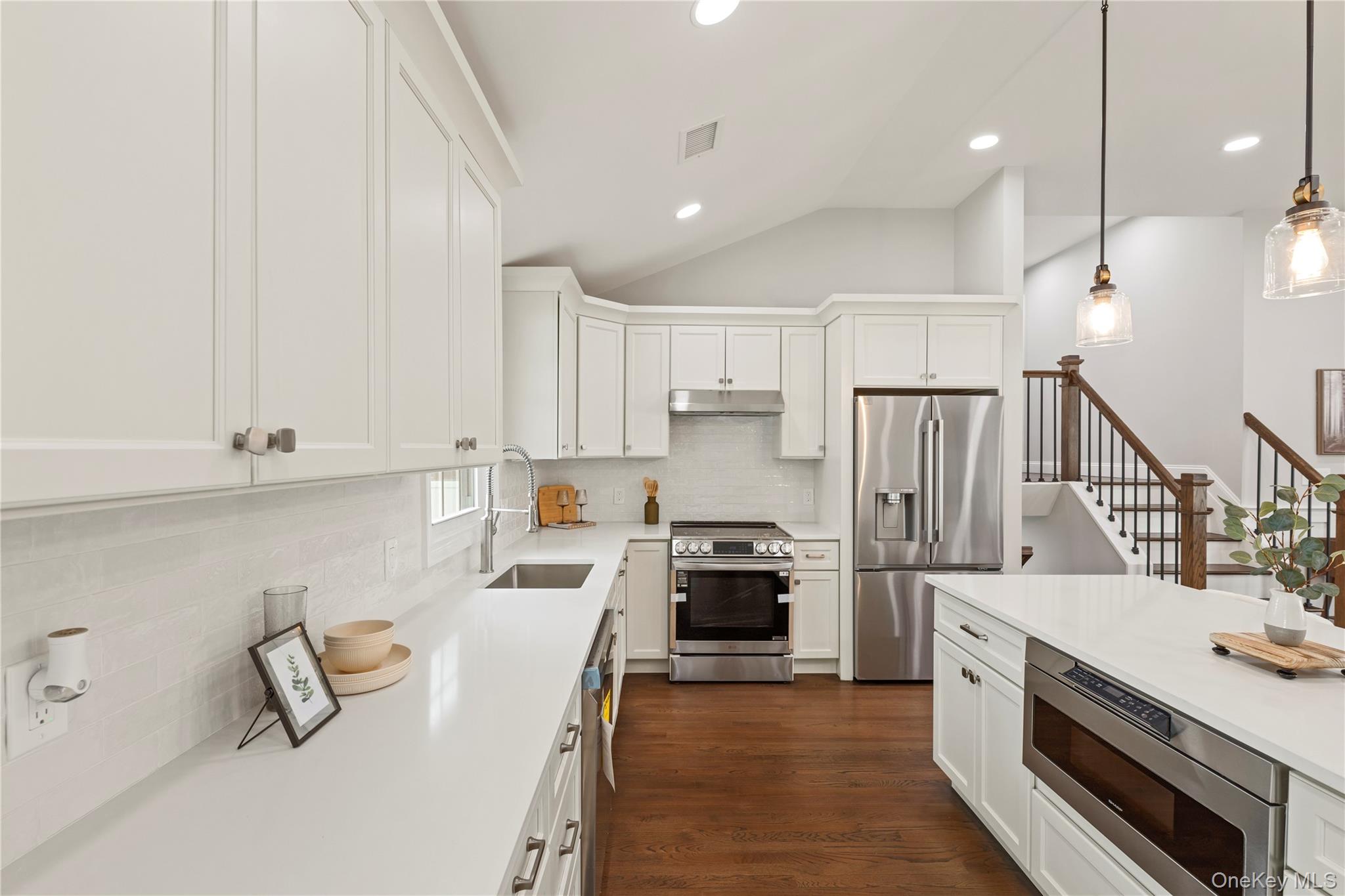 16 Eleanor Road Plainview, NY 11803 - Photo 9 of 28 Open-concept kitchen featuring white shaker cabinetry, stainless steel appliances, white countertops, and wood-finish flooring