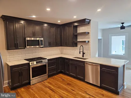 a modern kitchen with stainless steel appliances wooden floor and large window