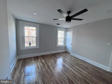 a view of a hallway with wooden floor and a bathroom